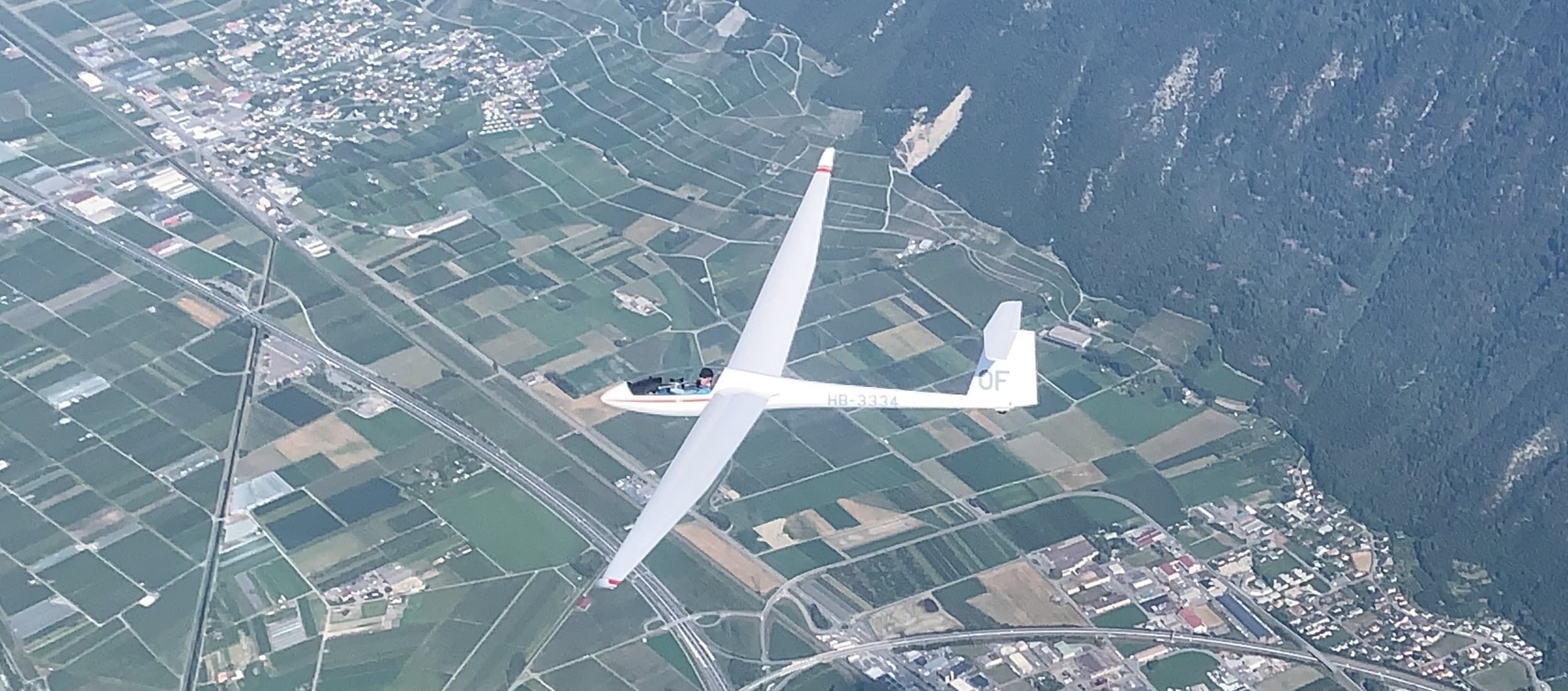 Planeur survolant la plaine, les champs et les Préalpes fribourgeoises